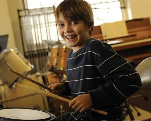 A Settlement student smiles while practicing the drums