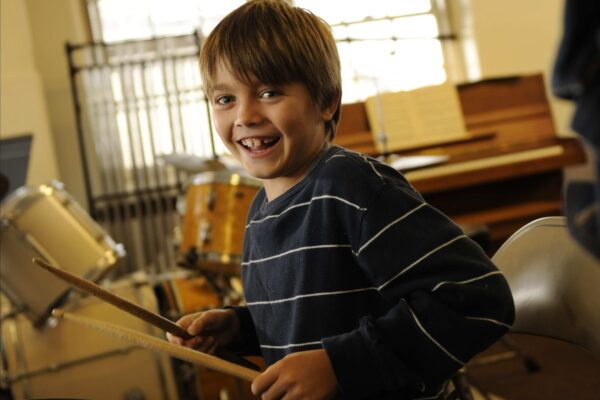 A Settlement student shows off his drumming skills with a smile
