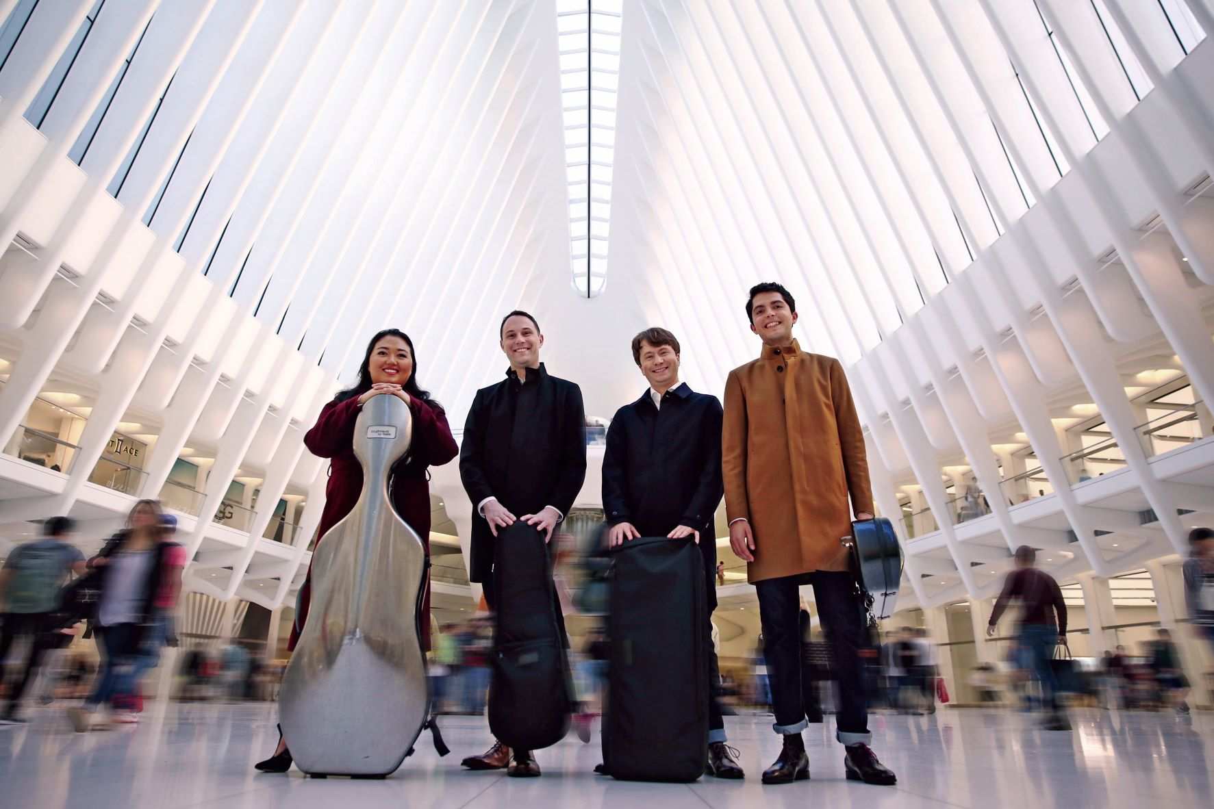 Members of the Calidore String Quartet pose with their instrument cases inside the Oculus in New York City.